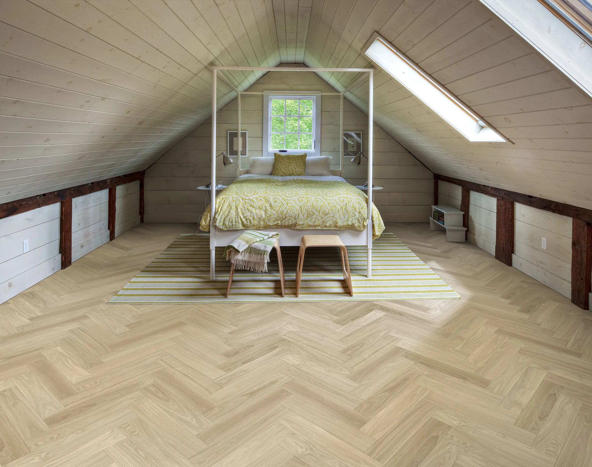 Attic bedroom with a sloped ceiling, featuring a bed with yellow bedding, a striped rug, and wooden floors. Natural light from skylights.
