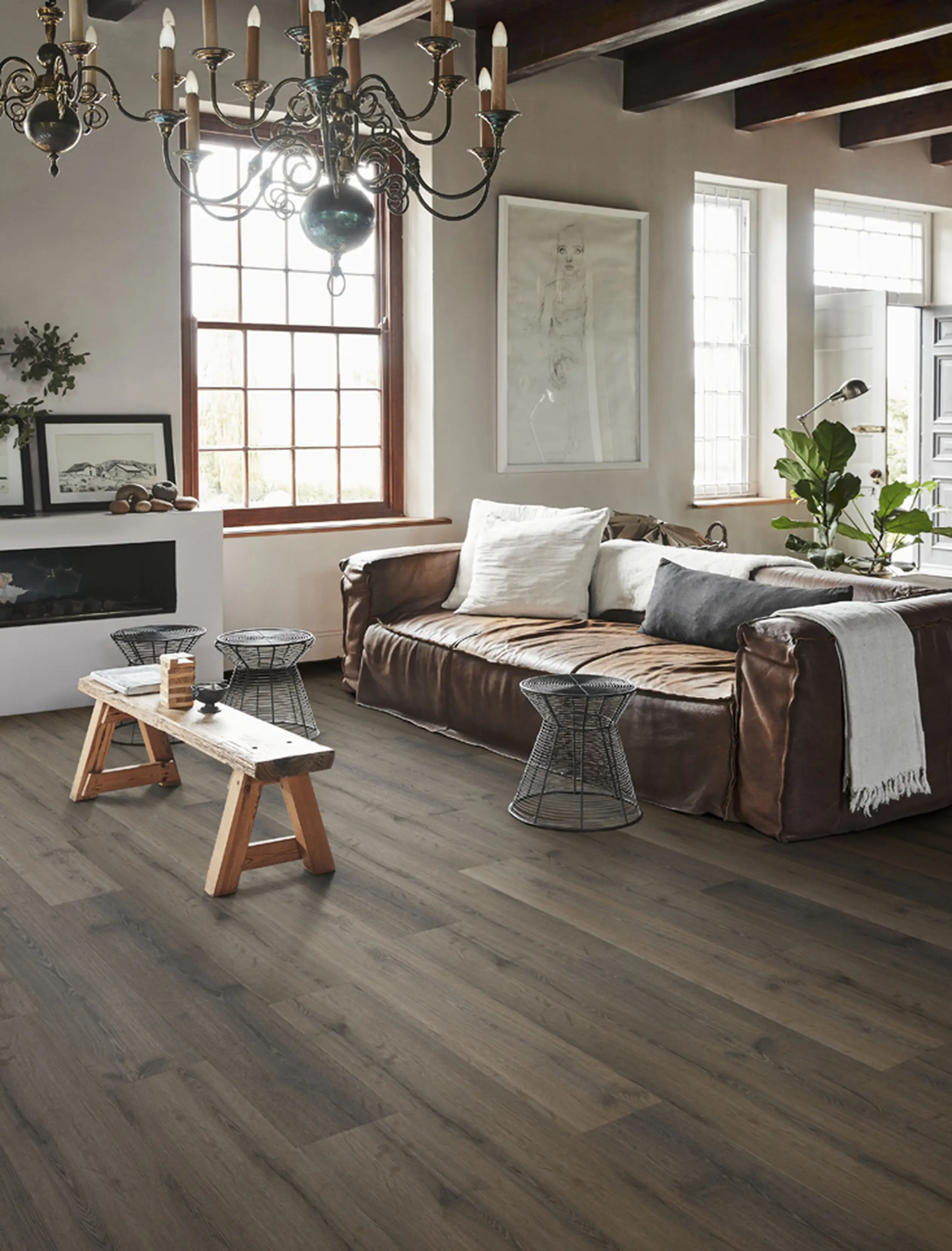 Cozy living room with dark wood flooring, a leather sofa, and rustic decor.