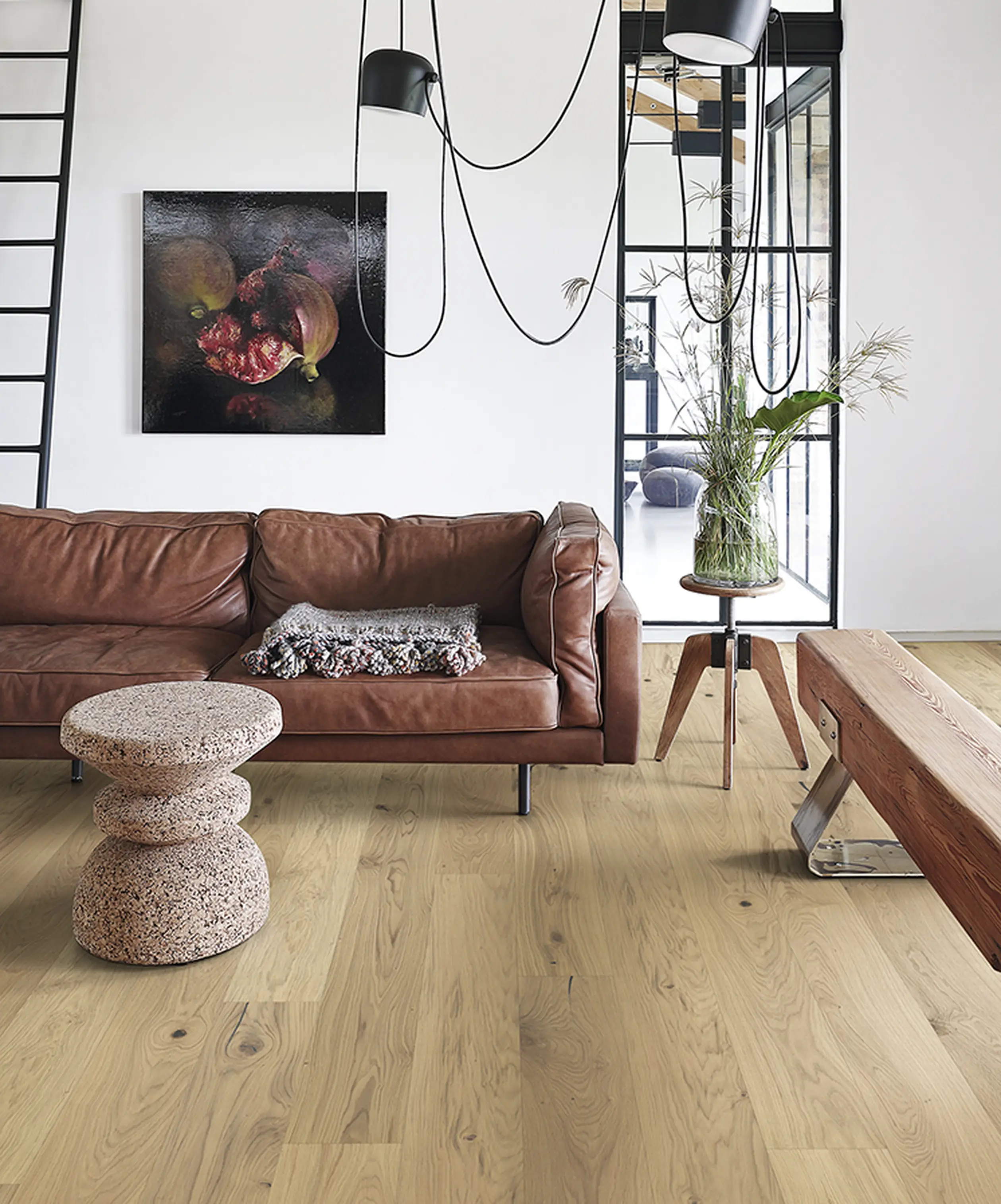 Contemporary living room with light wood flooring, a leather sofa, and artistic decor.