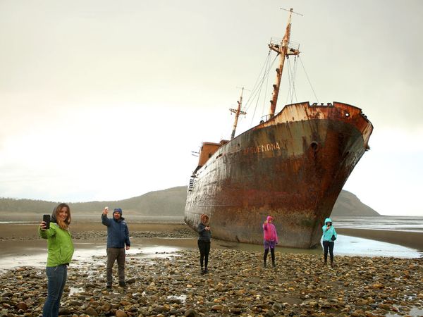 Visitors explore the rusted shipwreck of the Femina beached on rocky shores near Cabo San Pablo in Patagonia.
