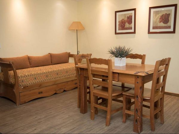 Rustic wooden furniture in a cozy common area at Hostal del Bosque in Ushuaia, featuring a dining table and sofa with traditional décor.