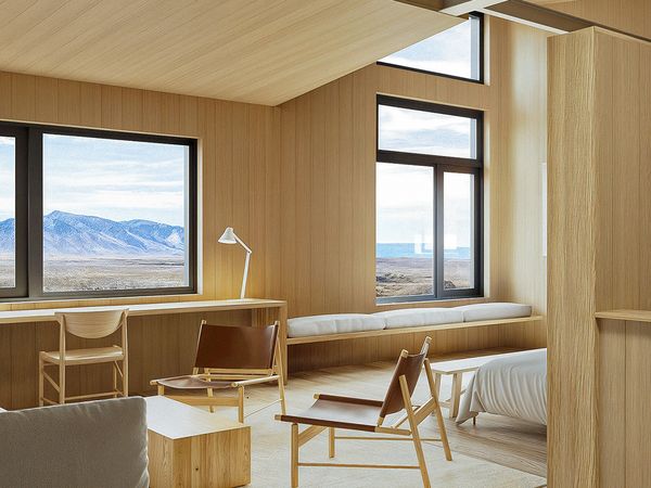 Modern minimalist lodge interior with panoramic windows overlooking Patagonian steppe and mountains in southern Chile.