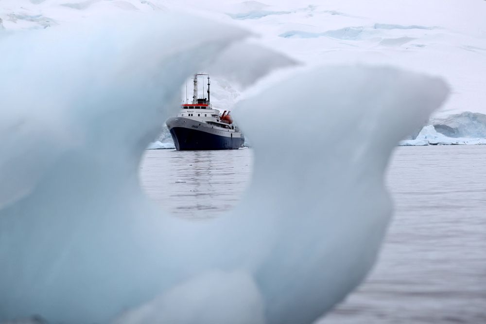 Research vessel navigates through icebergs in Antarctic waters during polar expedition.