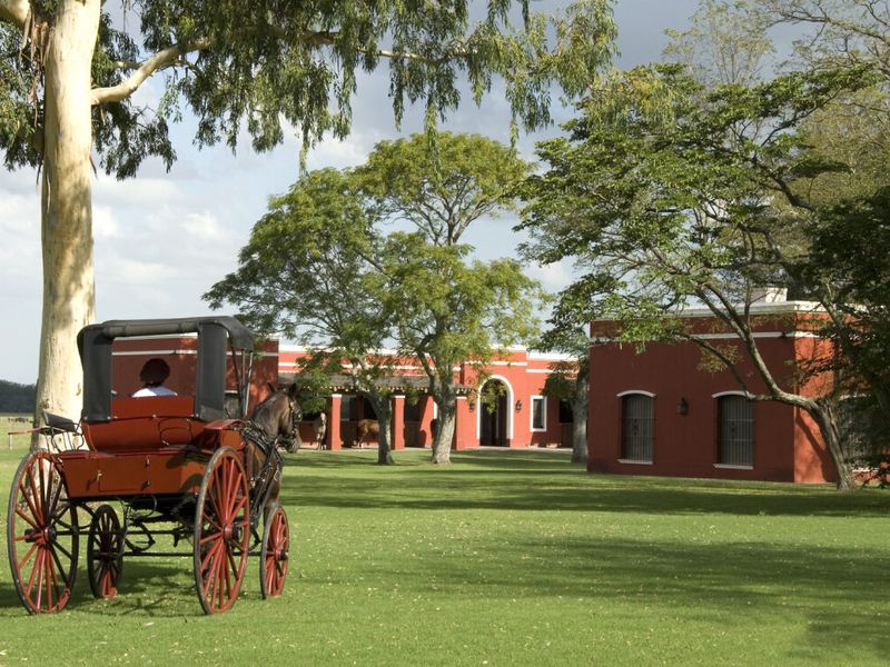Red horse-drawn carriage on the grounds of La Bamba de Areco historic estancia near Buenos Aires, Argentina.