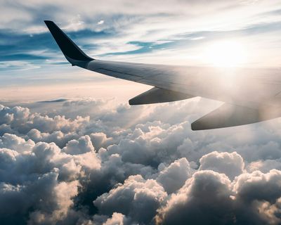 Airplane wing flying above clouds during sunset over South America.