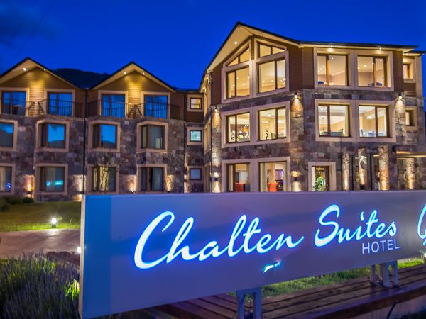 Chalfen Suites Hotel illuminated at dusk in El Chaltén, Patagonia, with stone architecture and warm interior lighting.