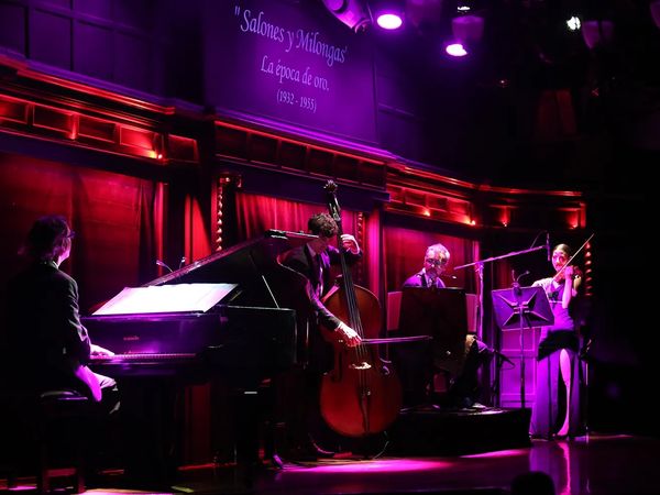Jazz musicians perform in intimate red and purple lighting at El Querandi, a historic tango venue in Buenos Aires.