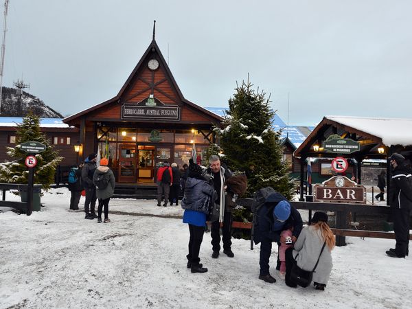 Tren Fin del Mundo station in Ushuaia with visitors gathering in the snowy plaza before boarding the historic train.