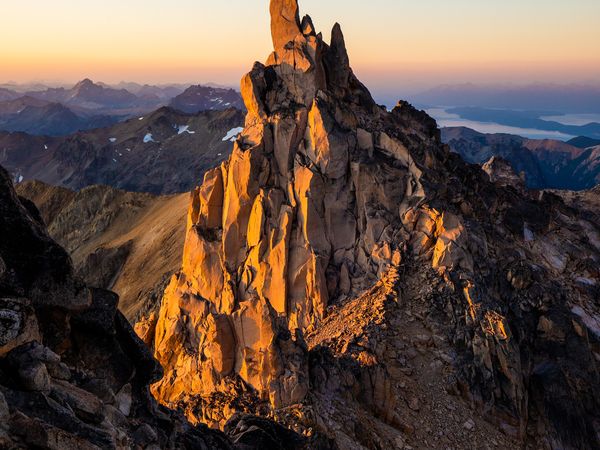 Dramatic rocky spire illuminated by golden sunrise light above alpine terrain near Bariloche, Patagonia.