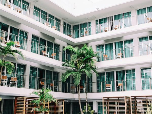 Modern hotel courtyard with palm trees and balconies overlooking a tropical resort in South America.