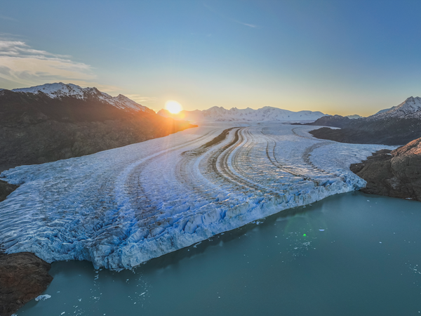 Glaciar Viedma flows through turquoise meltwater lakes at sunset, surrounded by snow-capped Patagonian mountains.