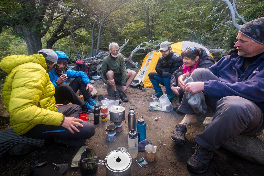 Backpackers gather around a camp stove in a forest clearing during a trek near El Chaltén, Patagonia.