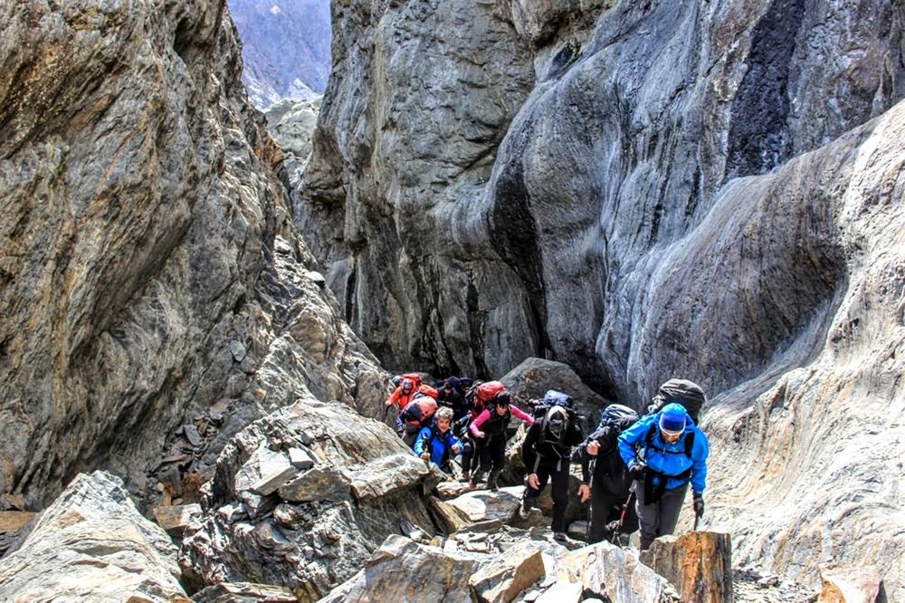 Group of trekkers hiking through narrow rocky canyon on Circuito Huemul trail near Glaciar Viedma in El Chaltén.