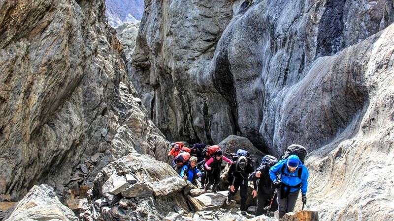 Group of trekkers hiking through narrow rocky canyon on Circuito Huemul trail near Glaciar Viedma in El Chaltén.