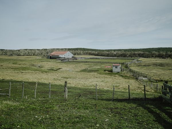 Rustic farm buildings with corrals scattered across rolling green pastures near Cabo San Pablo in Patagonia.
