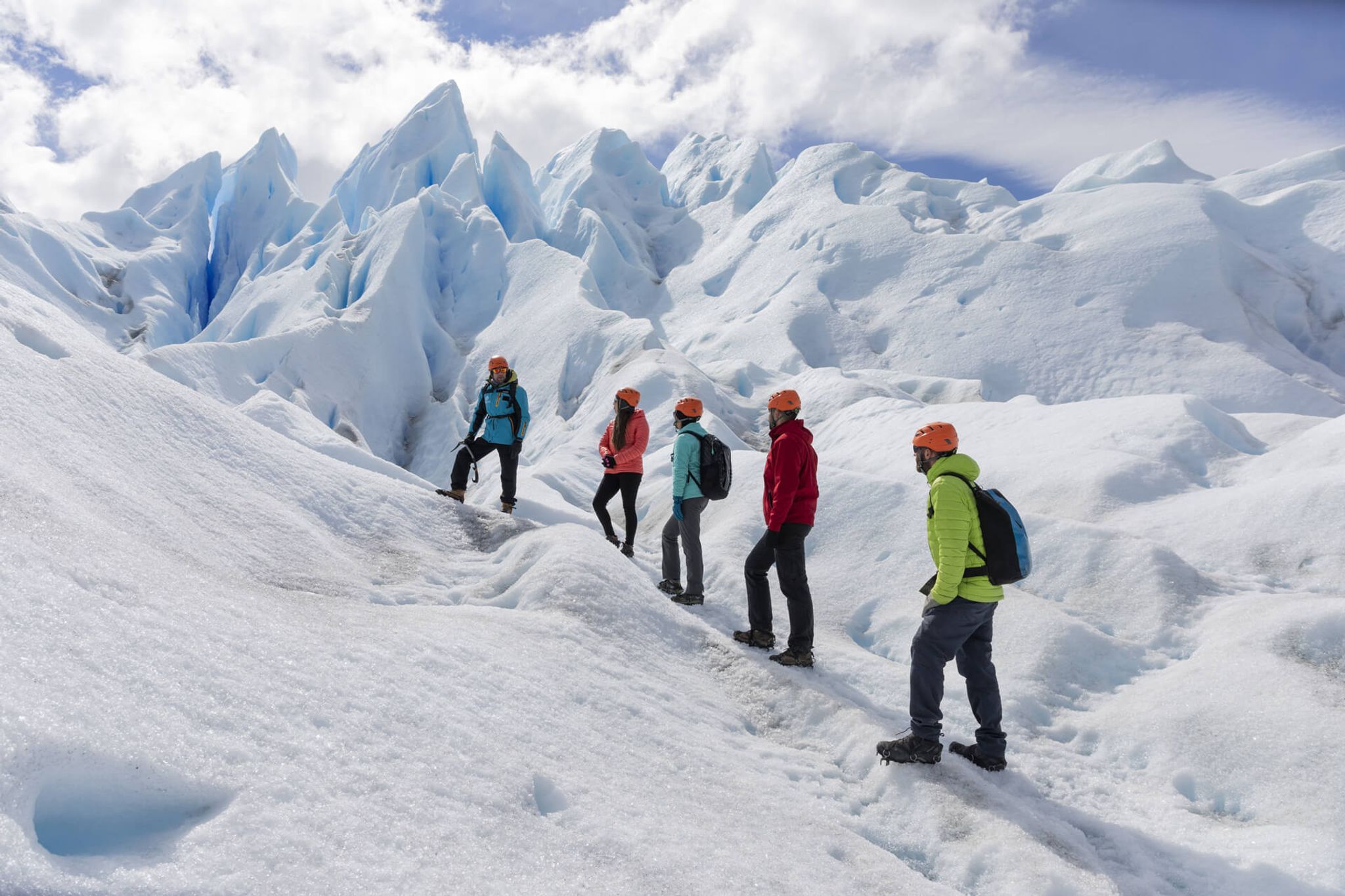 Group of trekkers exploring the stunning blue ice formations and crevasses of Glaciar Perito Moreno in El Calafate.