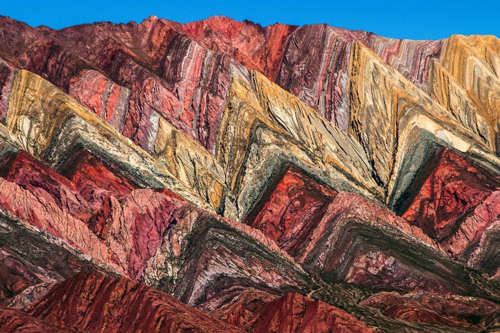 Vibrant multicolored rock formations of Serranía del Hornocal mountain range near Salta, Argentina displaying layers of red, yellow, and green mineral deposits.