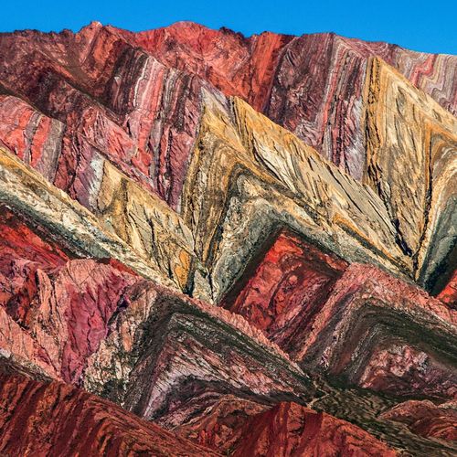 Vibrant multicolored rock formations of Serranía del Hornocal mountain range near Salta, Argentina displaying layers of red, yellow, and green mineral deposits.