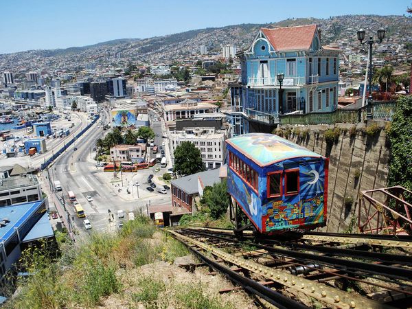 Colorful funicular cable car overlooking Valparaíso's hillside neighborhoods, harbor, and iconic blue Victorian architecture.
