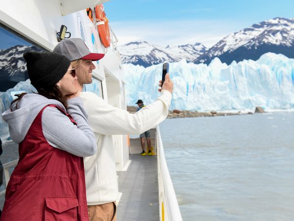 Tourist photographing Perito Moreno Glacier from a boat tour in Patagonia, Argentina.