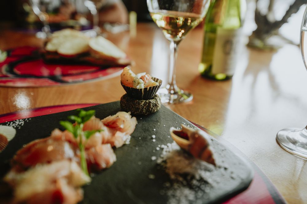 Elegant fine dining plating with fresh seafood, garnished herbs, and white wine at a Ushuaia Beagle Channel gourmet restaurant.