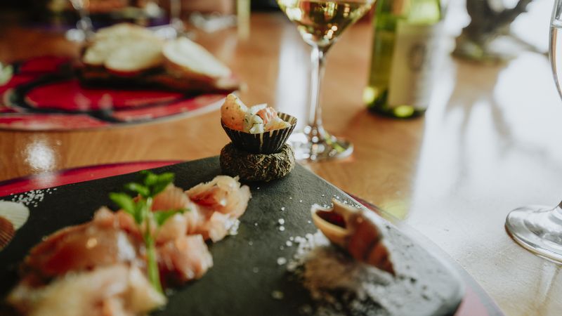 Elegant fine dining plating with fresh seafood, garnished herbs, and white wine at a Ushuaia Beagle Channel gourmet restaurant.