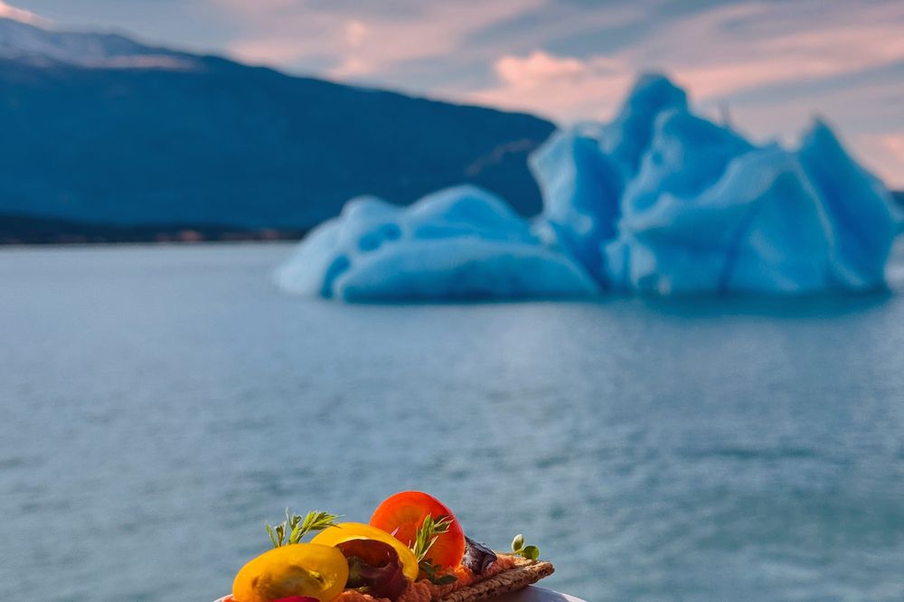 Gourmet soup with fresh vegetables overlooking a blue iceberg in Glaciar Perito Moreno, El Calafate.