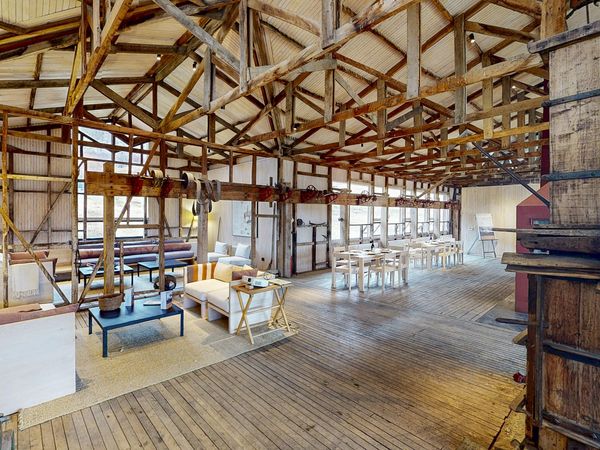 Spacious converted warehouse interior at Explora with rustic wooden beams, modern furnishings, and open-plan design.