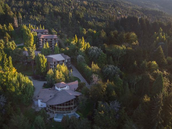 Aerial view of Design Suites luxury resort nestled among golden larch trees in Bariloche, Patagonia.