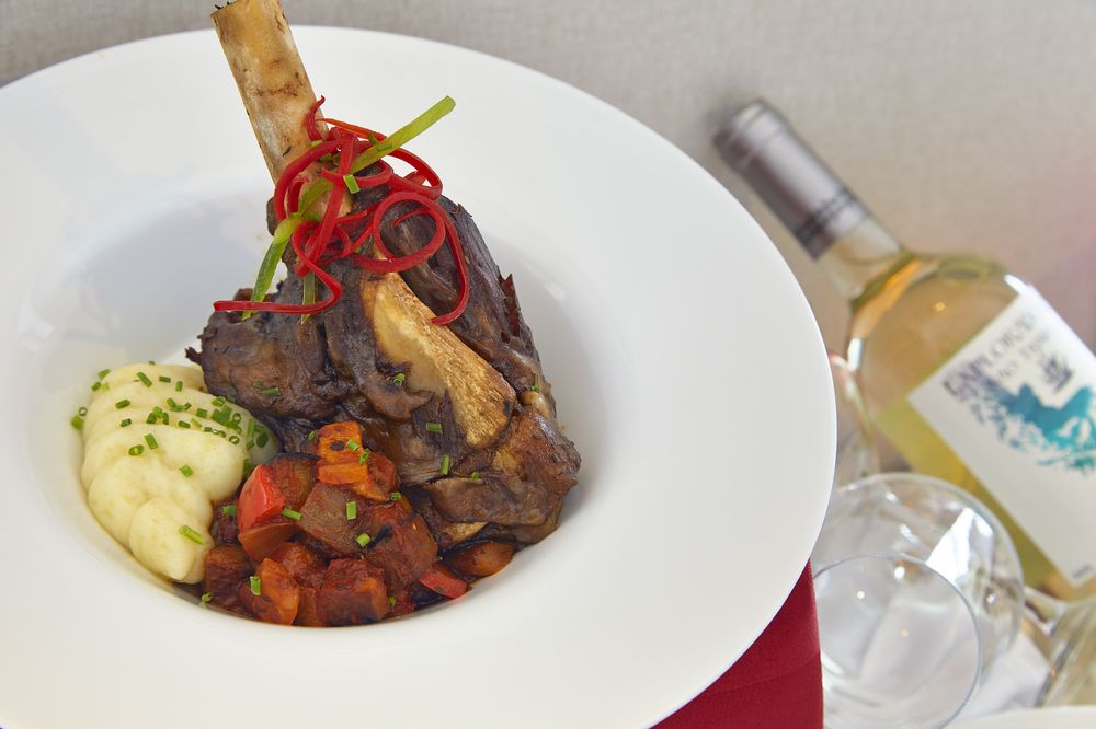 Grilled lamb chop with mashed potatoes and red pepper garnish paired with white wine in Patagonia.