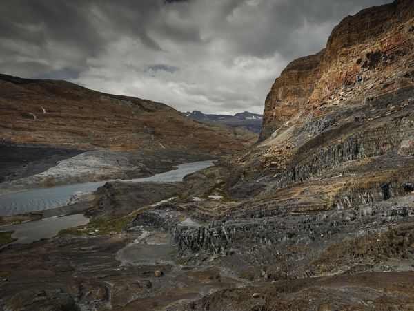 Glacial meltwater streams wind through rugged Patagonian terrain beneath towering rock cliffs at Estancia Cristina.