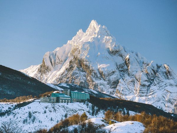 Snow-capped mountain peak rises behind the Arakur hotel nestled in a winter valley landscape.