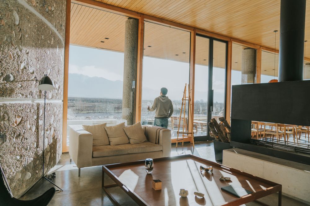 Modern Mendoza winery lounge with panoramic valley views, fireplace, and contemporary furnishings overlooking vineyards.