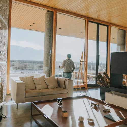 Modern Mendoza winery lounge with panoramic valley views, fireplace, and contemporary furnishings overlooking vineyards.