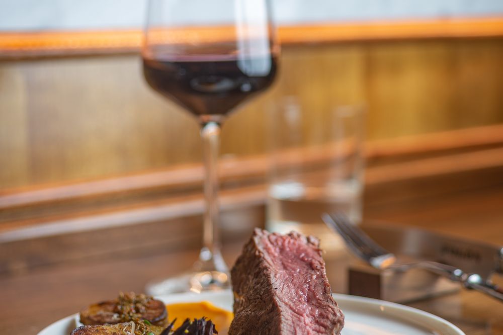 Medium-rare beef steak with roasted vegetables and red wine at an upscale Buenos Aires parrilla restaurant.
