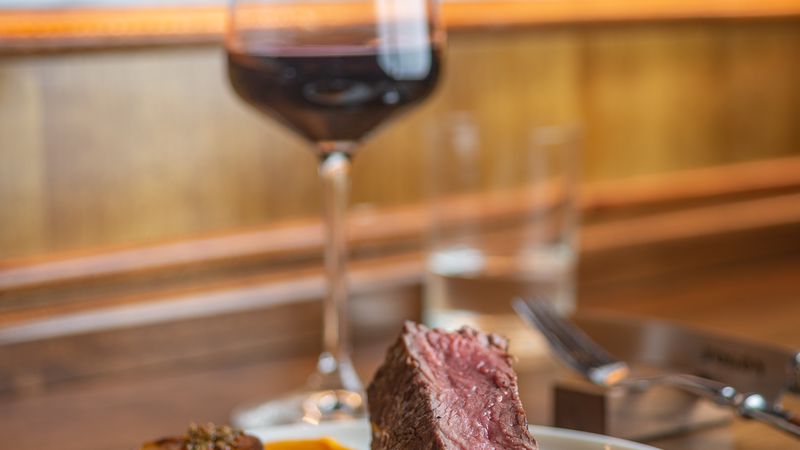 Medium-rare beef steak with roasted vegetables and red wine at an upscale Buenos Aires parrilla restaurant.