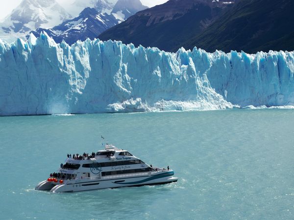 Tourists on a boat view the massive turquoise ice wall of Glaciar Perito Moreno in Patagonia, Argentina.