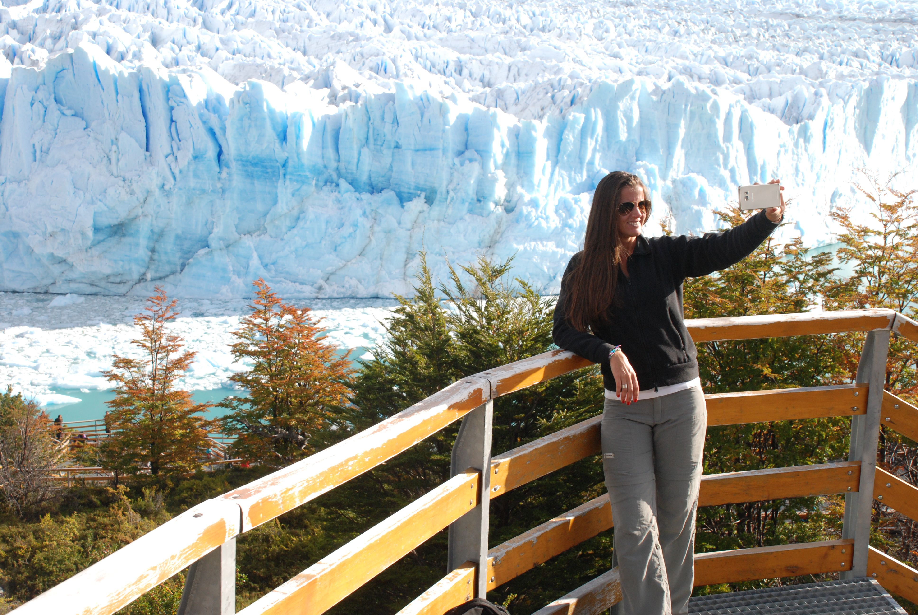 Woman taking a selfie on the viewing platform overlooking the stunning blue ice formations of Glaciar Perito Moreno in El Calafate, Patagonia.
