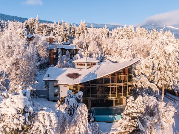 Luxury lodge nestled in snow-covered forest near Bariloche, Argentina, with modern architecture and mountain views.