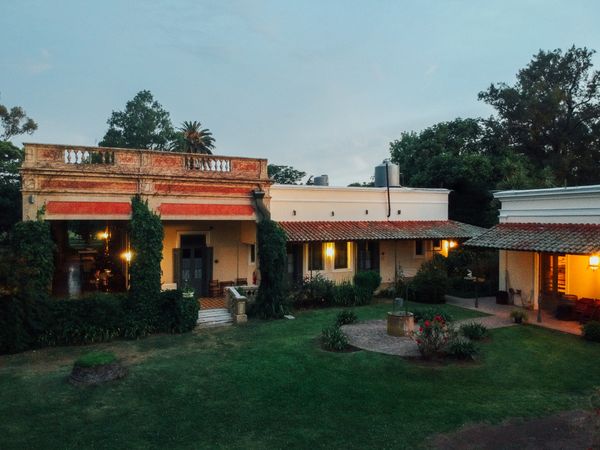 Colonial estancia with terracotta architecture and manicured grounds at dusk in San Antonio de Areco, Buenos Aires.