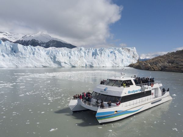 Tourist boat navigates icy waters before the massive white face of Perito Moreno Glacier in Los Glaciares National Park, Argentina.