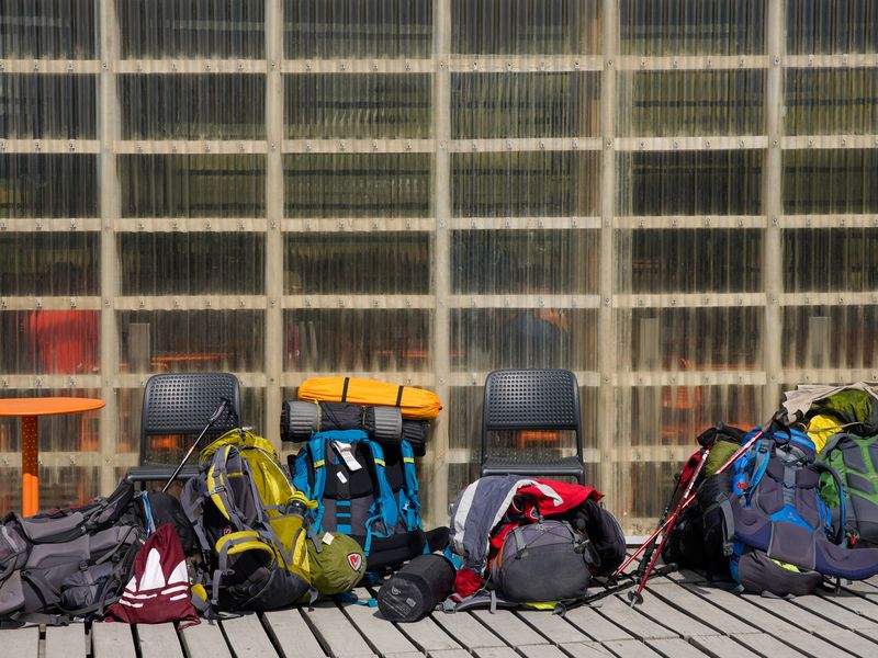 Colorful backpacks and hiking gear arranged on a wooden deck at Torres del Paine, Chile, ready for trekking adventures.