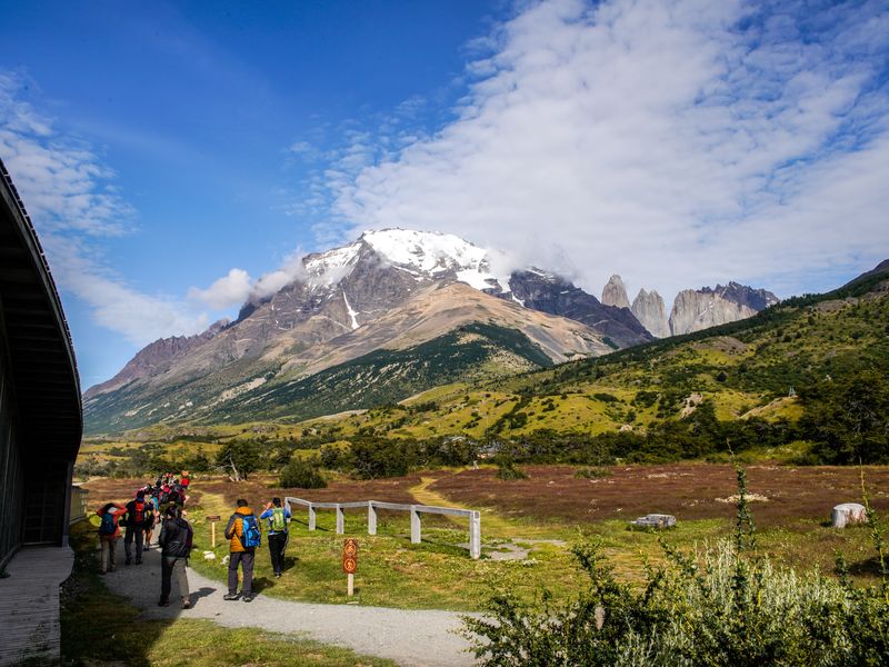 Hikers on the W Trek trail with snow-capped Mount Paine and the iconic Torres del Paine peaks in Torres del Paine National Park, Chile.
