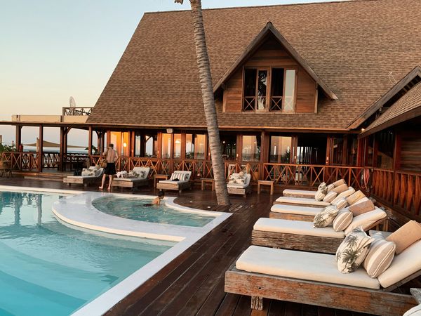 Luxury beachfront resort with wooden deck, infinity pool, and ocean views at sunset in tropical Patagonia.