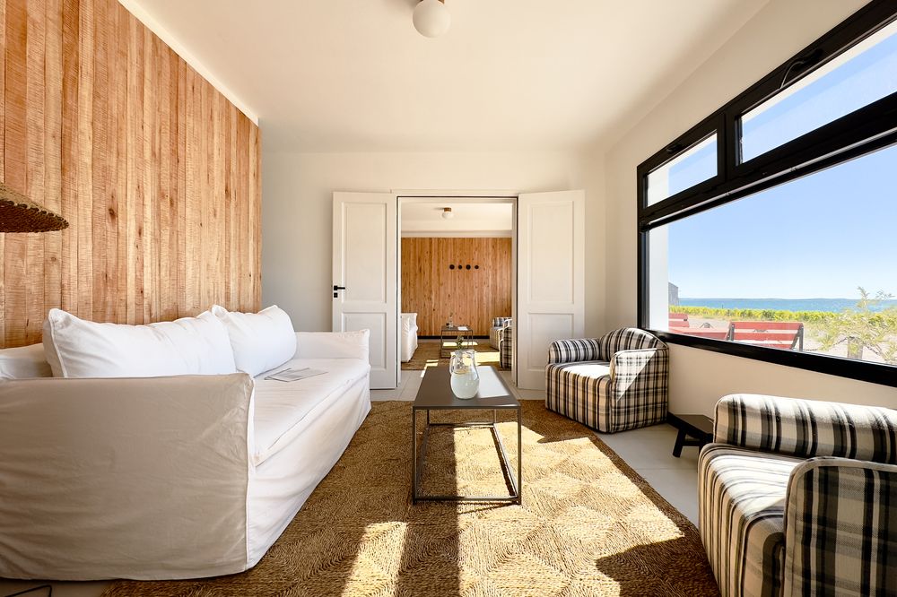 Luxurious living suite at Bahía Bustamante with ocean views, modern furnishings, and natural wood accents overlooking Patagonian coast.