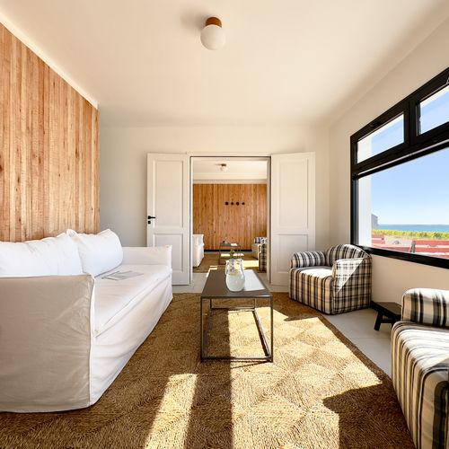 Luxurious living suite at Bahía Bustamante with ocean views, modern furnishings, and natural wood accents overlooking Patagonian coast.