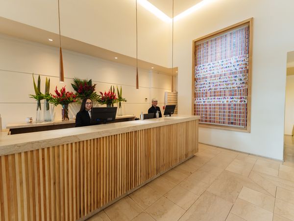 Modern hotel reception desk at Fierro Buenos Aires with elegant wood paneling, fresh flowers, and minimalist design.