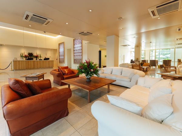 Loi Suites Recoleta hotel lobby featuring modern seating areas with cognac leather and cream upholstered furniture arranged around a wooden coffee table.