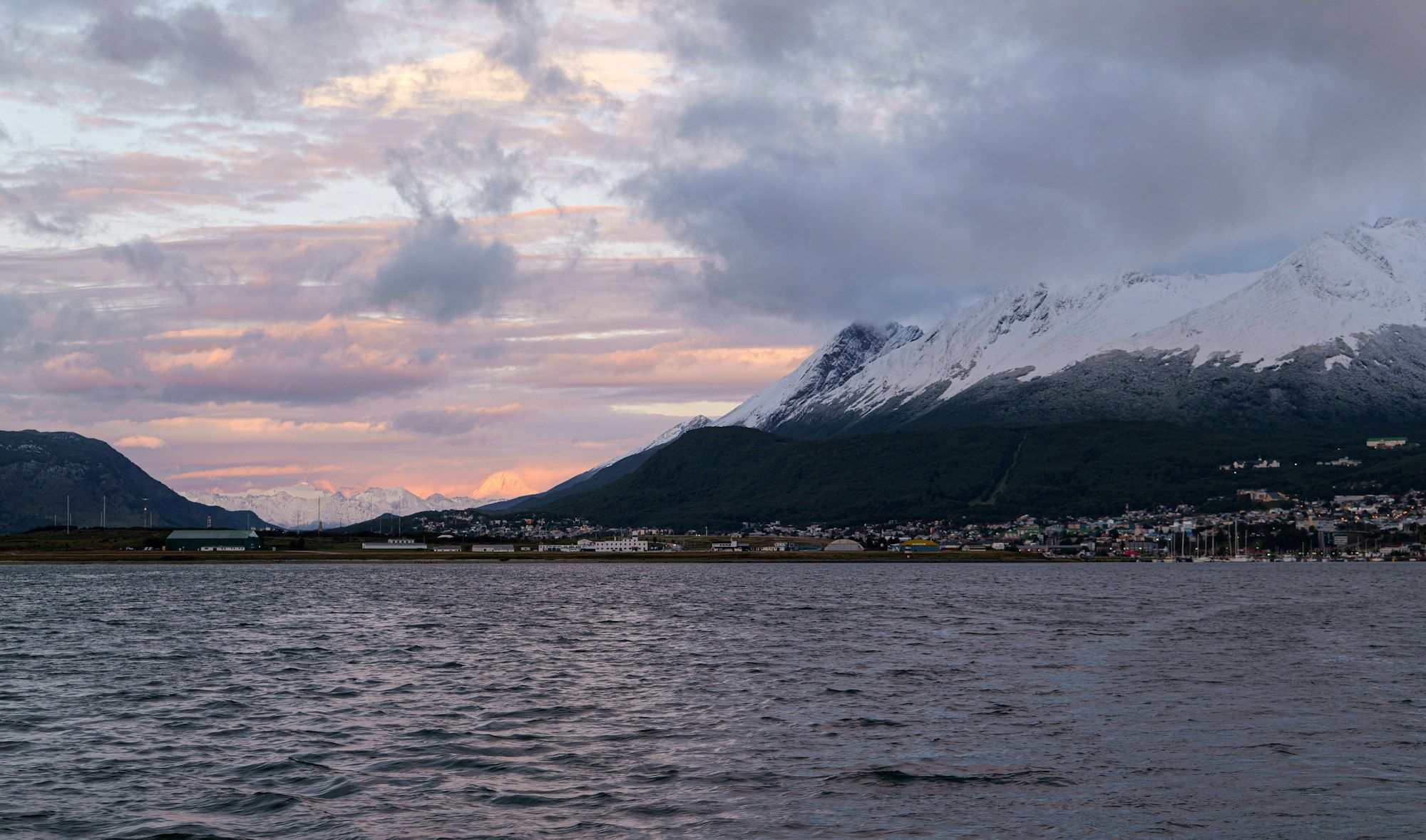 Snow-capped mountains frame the coastal town of Ushuaia along the Beagle Channel