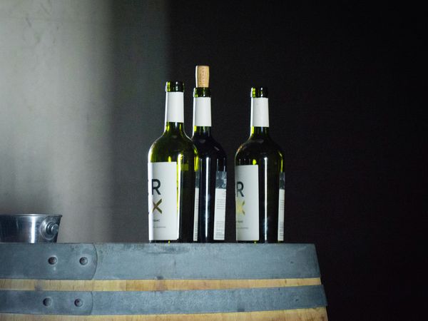 Three RX wine bottles displayed on a wooden barrel at a Buenos Aires wine tasting event.